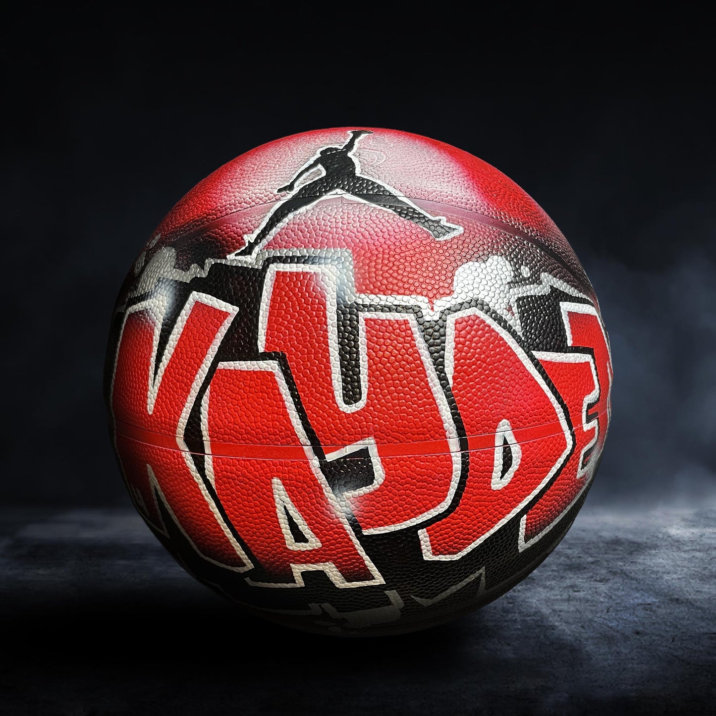A basketball with the name "KAYDEN" painted on it in red and black colors.