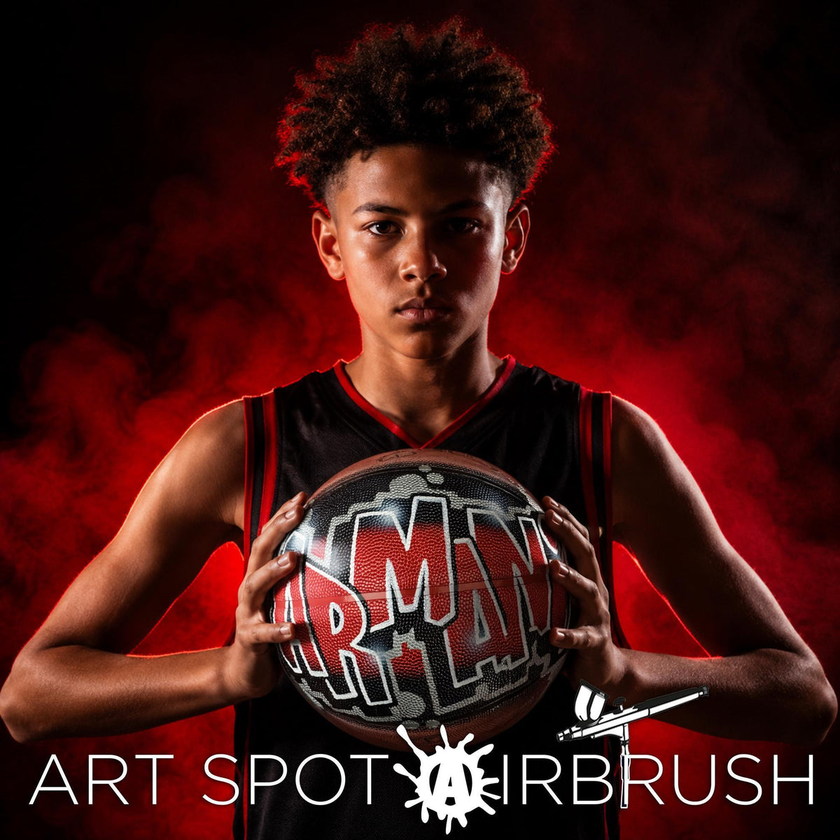 A young man with curly hair is holding a basketball with the word "ARMANI" on it, standing against a red background with smoke or fog.