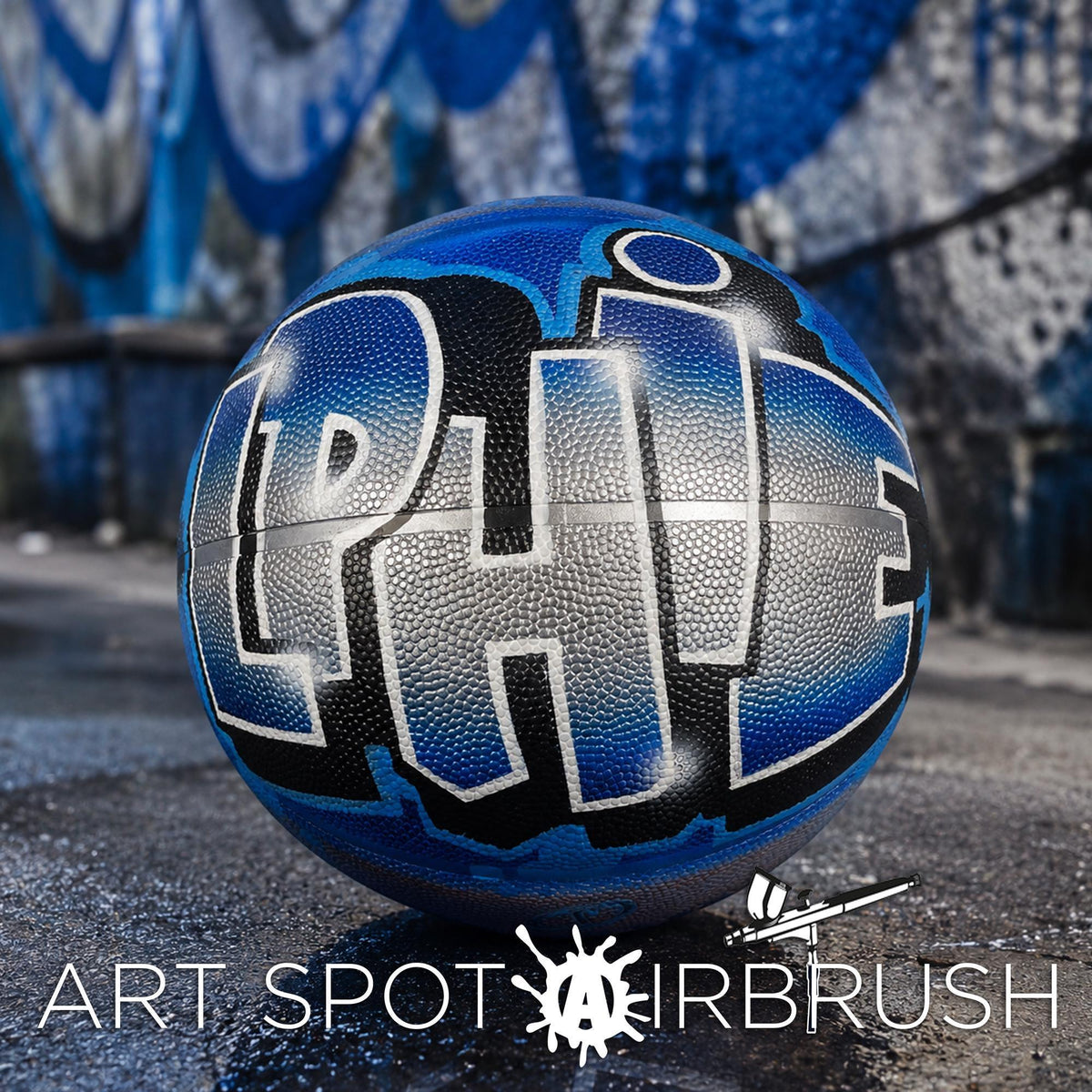 A blue basketball with the word "LPHE" painted on it, sitting on a surface with graffiti in the background.