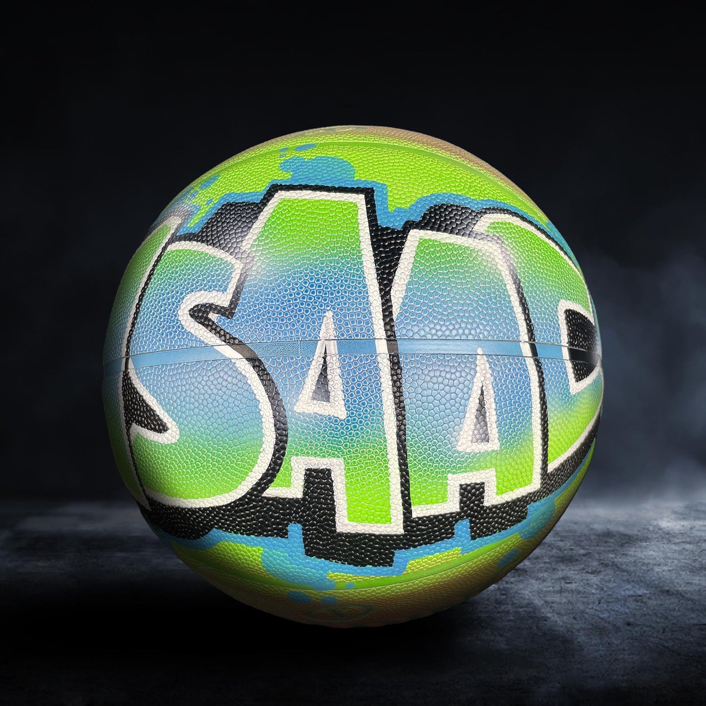 A basketball with the word "SAAP" painted on it in a colorful, graffiti-style design.