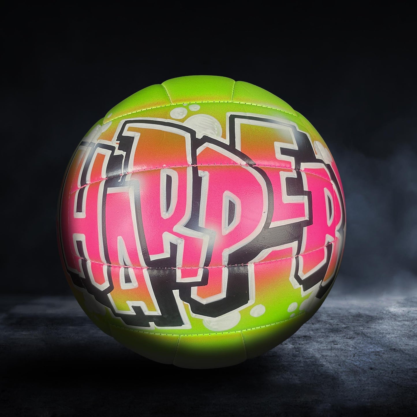 A neon green and pink soccer ball with the word "HARP" painted on it.
