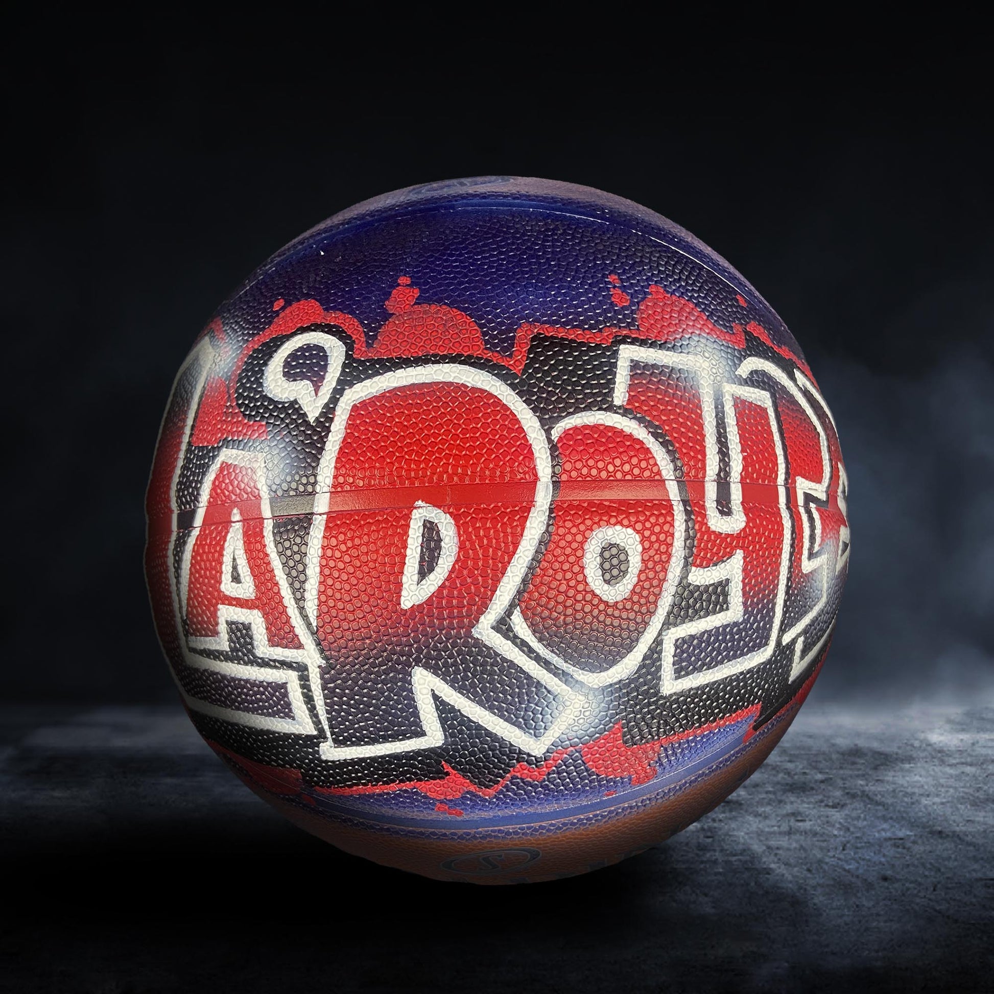 A basketball with the word "AROY" painted on it in red and black colors.