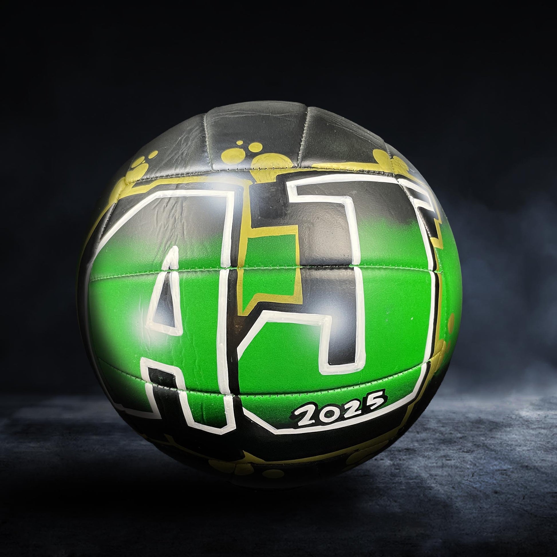 A green and black soccer ball with the number "42" and the year "2025" printed on it, set against a dark background.