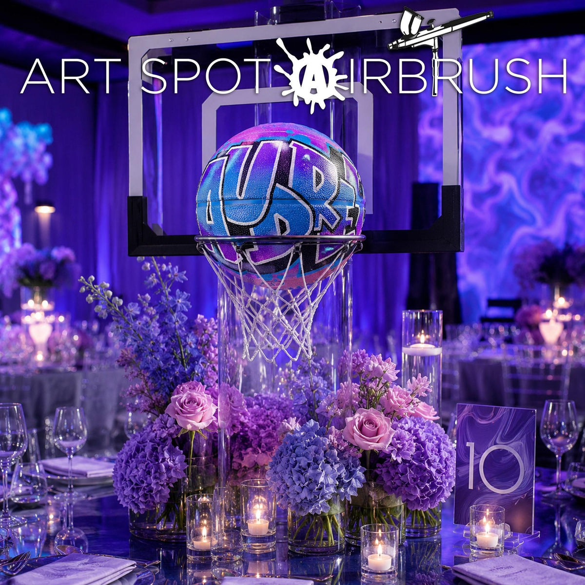 a basketball hoop decorated with purple and blue flowers, surrounded by a table set with candles and place settings, creating a festive atmosphere.