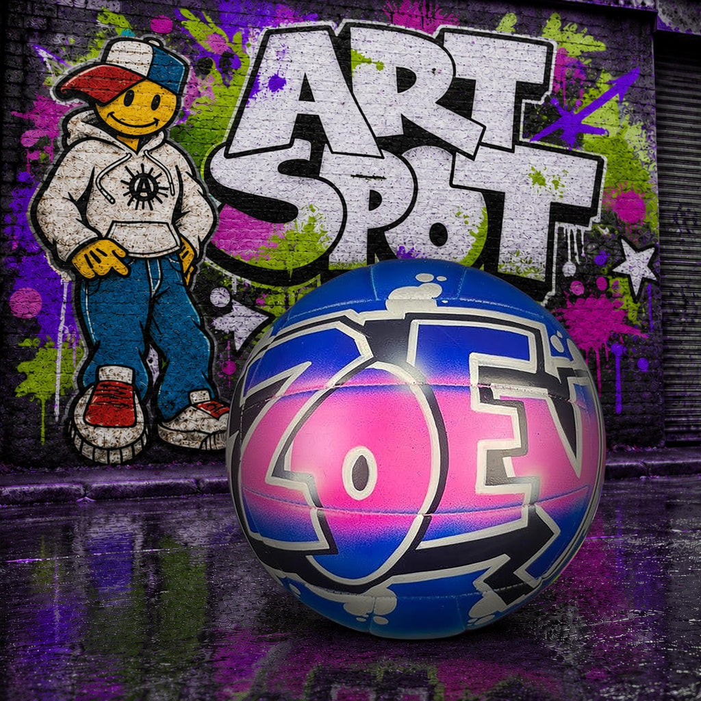 A colorful, graffiti-style custom volleyball, with the name ZOEY, placed in front of a graffiti-covered wall with a cartoon character and the name ART SPOT.