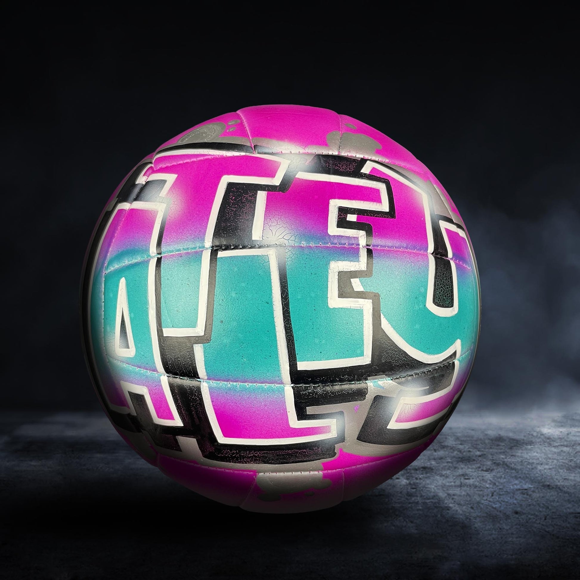 A colorful volleyball with the word "ALEX" painted on it, set against a dark background.