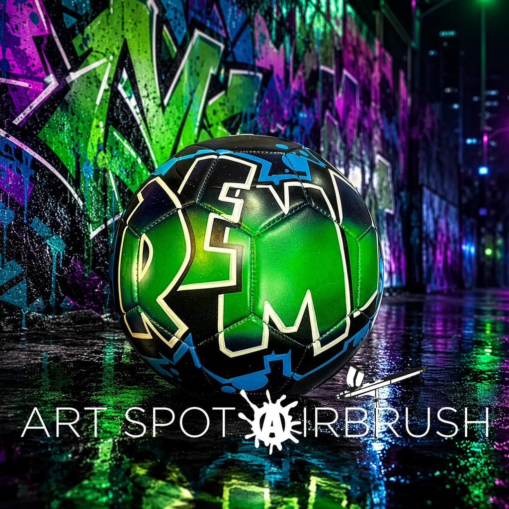 A soccer ball with colorful graffiti on it is displayed in front of a vibrant, graffiti-covered wall at night.