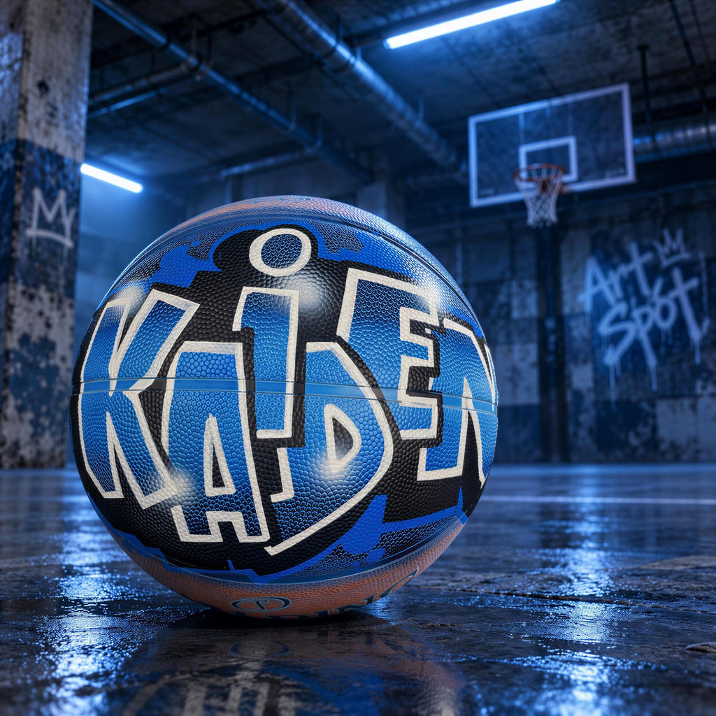 A basketball with the name "Kaiden" painted on it, sitting on a wet basketball court with graffiti on the walls in the background.