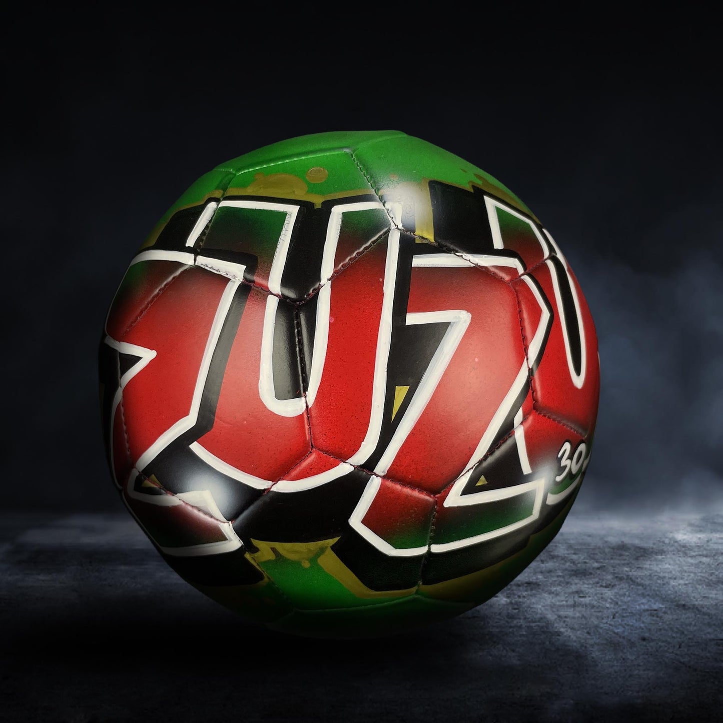A colorful soccer ball with the word "ZUZ" painted on it, set against a dark background.