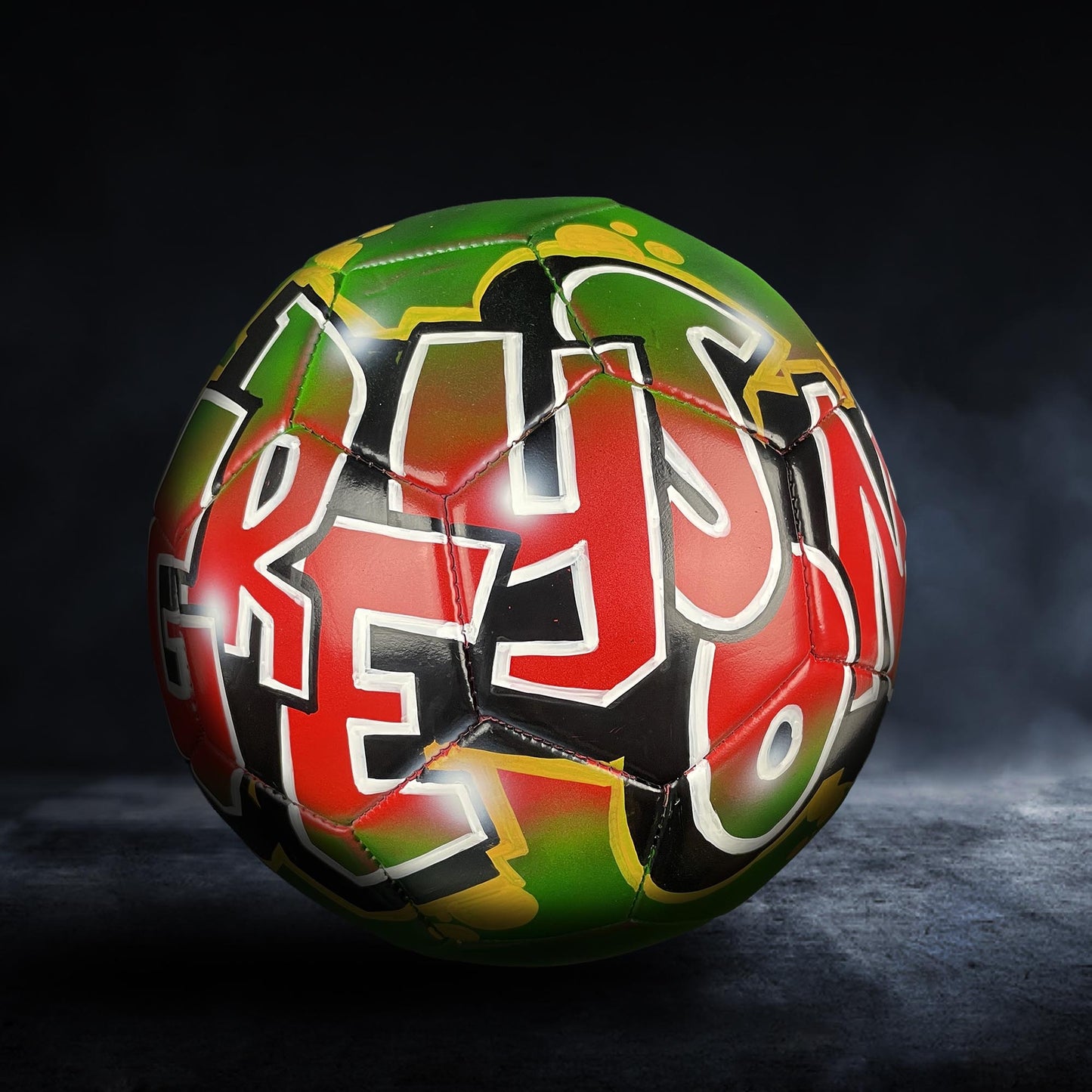 A colorful soccer ball with graffiti-style lettering on it, set against a dark background.
