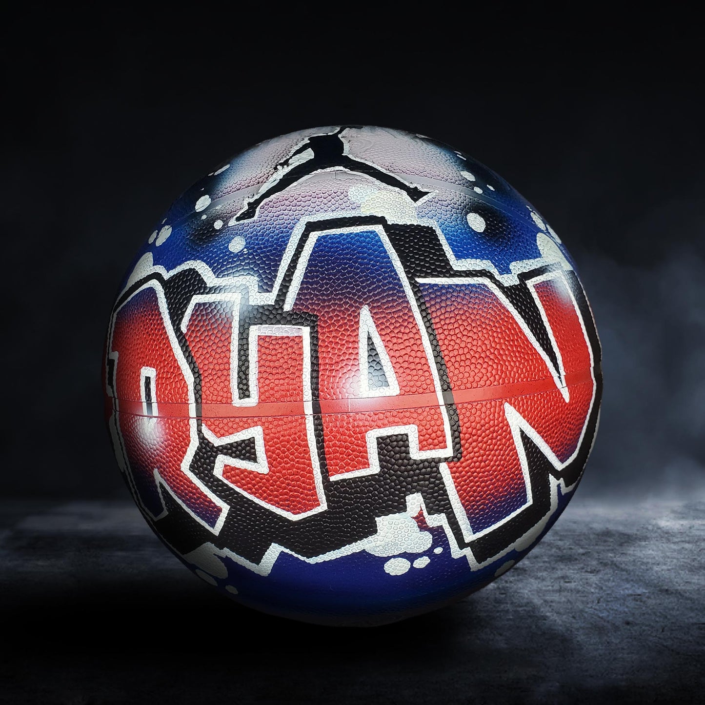 A basketball with the name "Ryan" painted on it in a colorful, graffiti-style design.