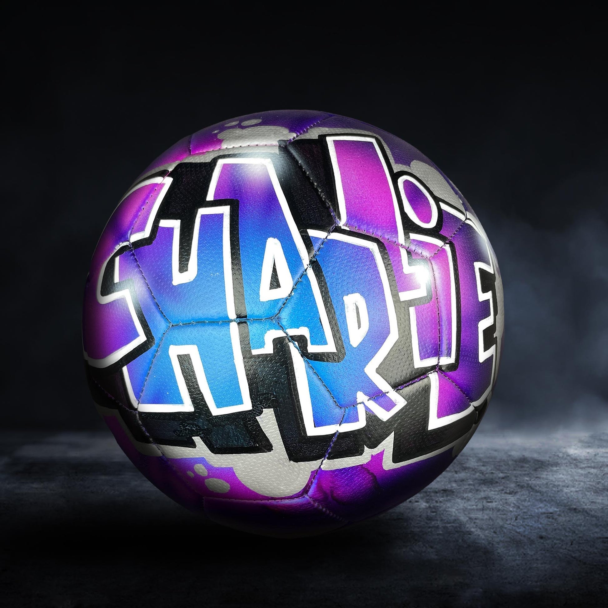 A soccer ball with the name "Charlie" painted on it in a colorful, graffiti-style design.
