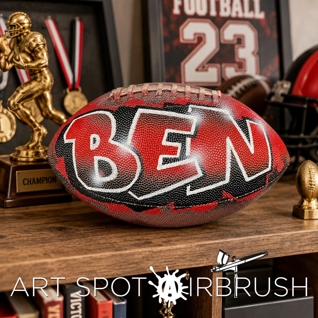 a custom football personalized with the name "Ben" painted on it, placed on a wooden surface. In the background, there are various sports memorabilia, including a trophy, a framed football jersey, and a framed picture of a football.