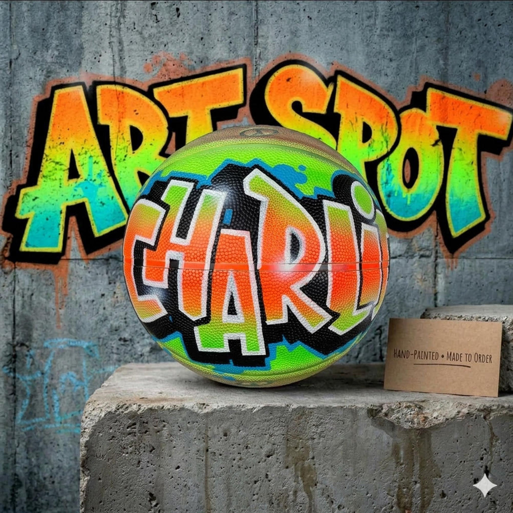 A colorful basketball with the name "Charl" painted on it, sitting on a concrete ledge in front of a graffiti-covered wall.