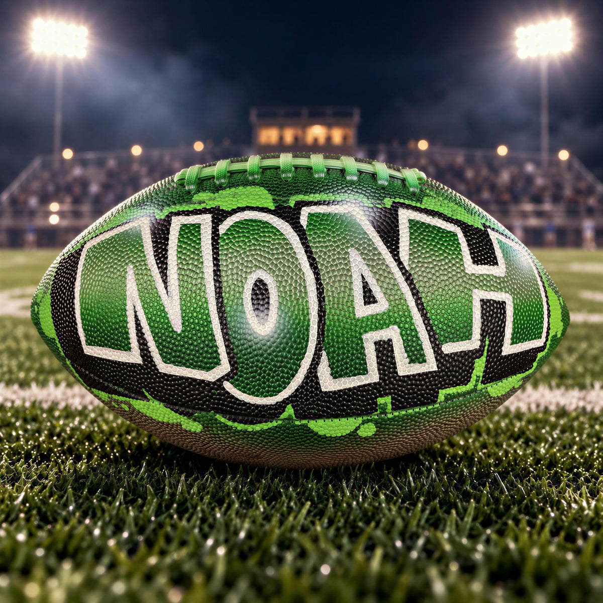 A green and black football with the word "Noah" painted on it, sitting on a grassy field at night with stadium lights in the background.