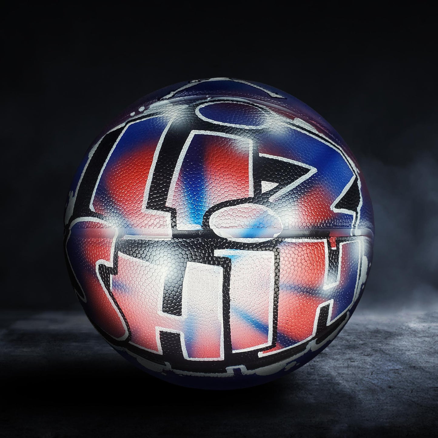 A basketball with a colorful, graffiti-style design on its surface, featuring a mix of red, blue, and black colors.