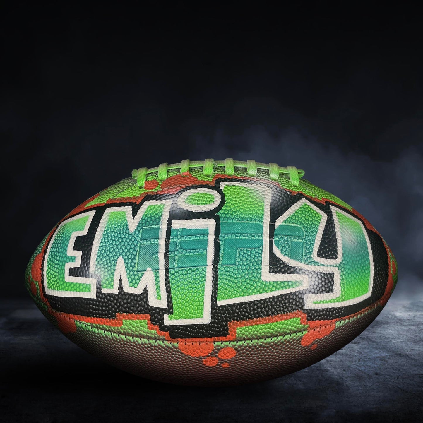A personalized football with the name "Emilie" painted on it, featuring a colorful and unique design.