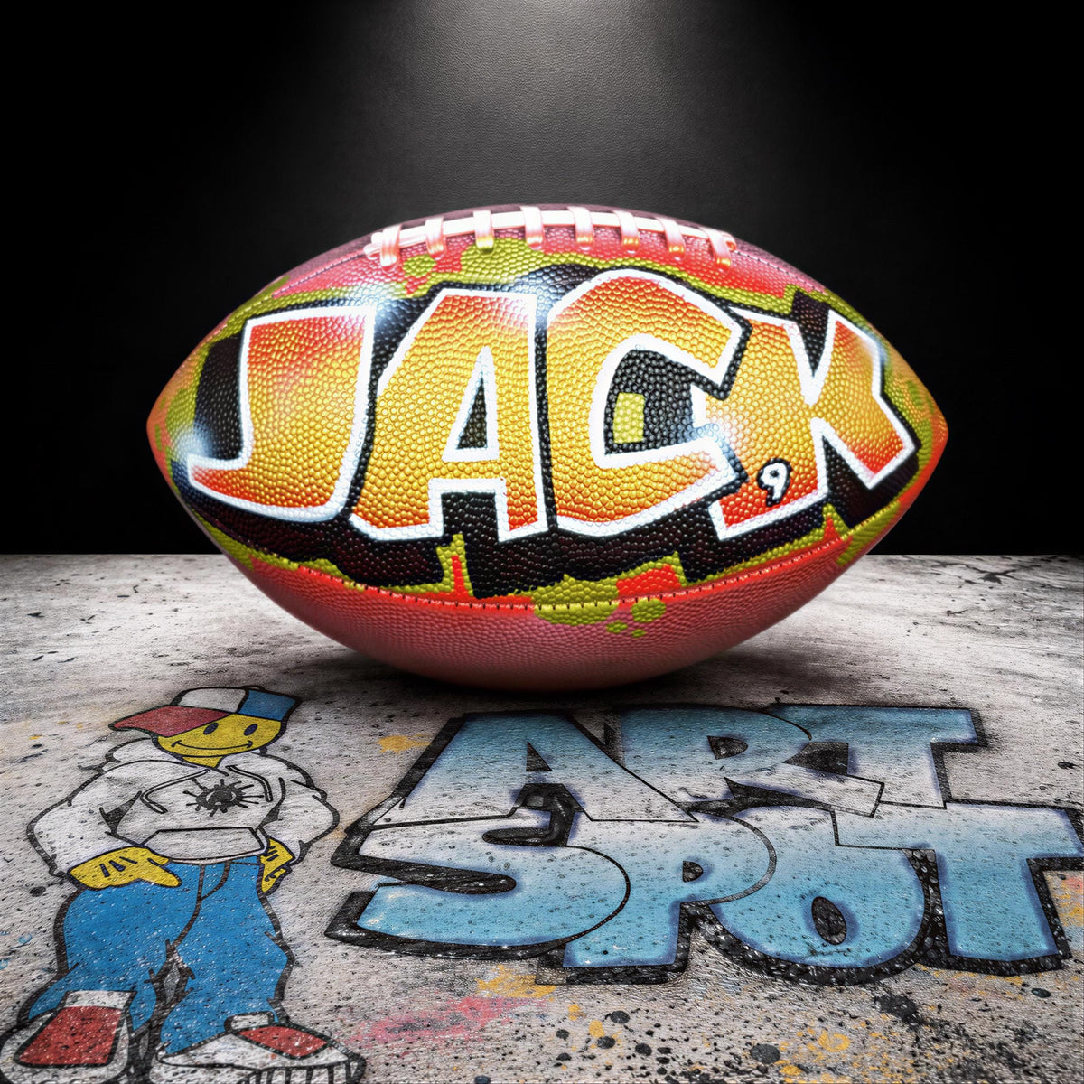 A colorful football with the name "JACK" written on it, placed on a surface with graffiti art.