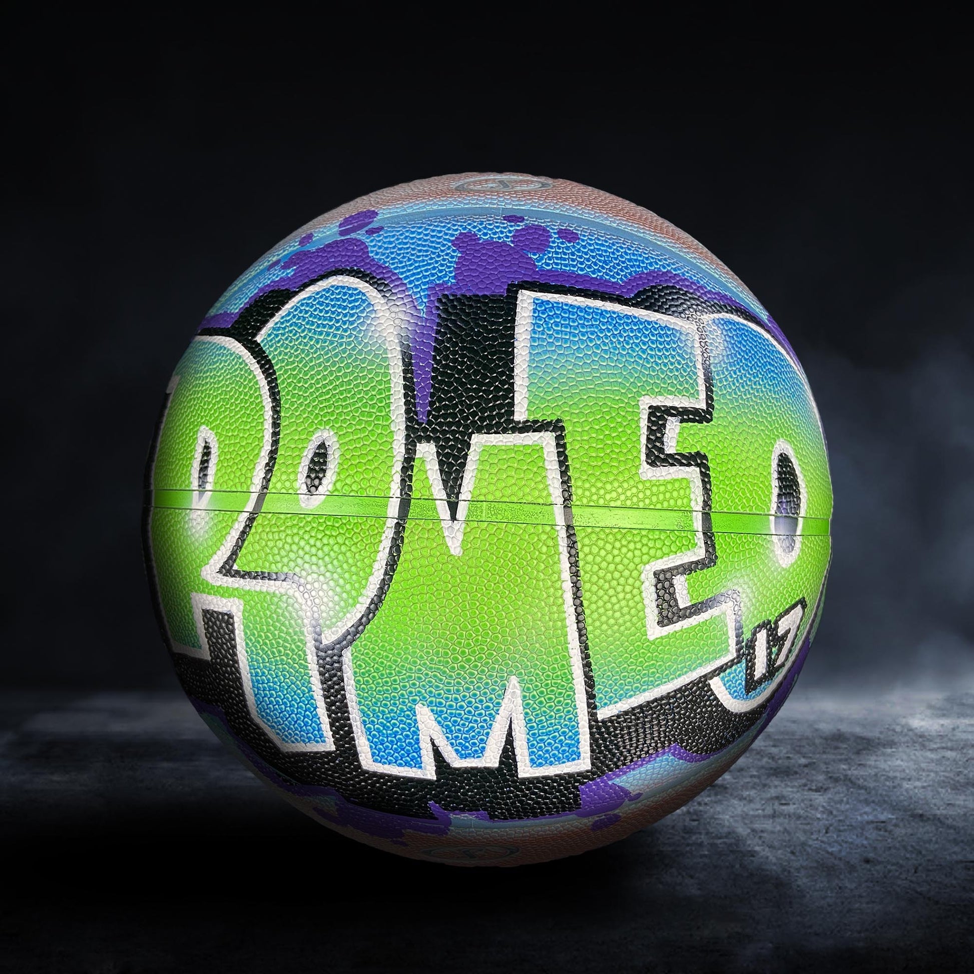 A colorful basketball with the word "ROMEO" painted on it, featuring a mix of green, blue, and purple colors.