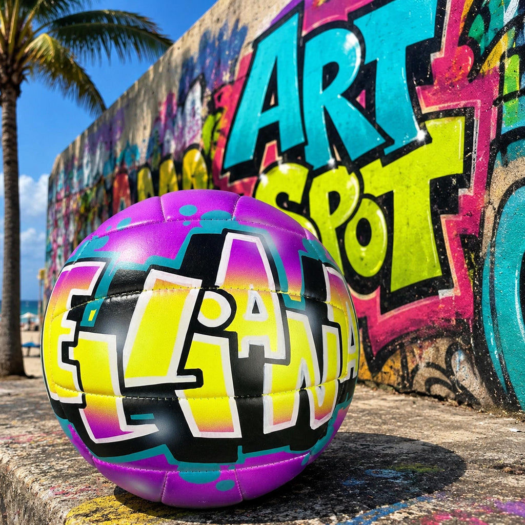 A colorful, graffiti-style custom volleyball with the word "ELLIANA" painted on it, sitting on a concrete surface in front of a vibrant, colorful graffiti wall with the name ART SPOT.