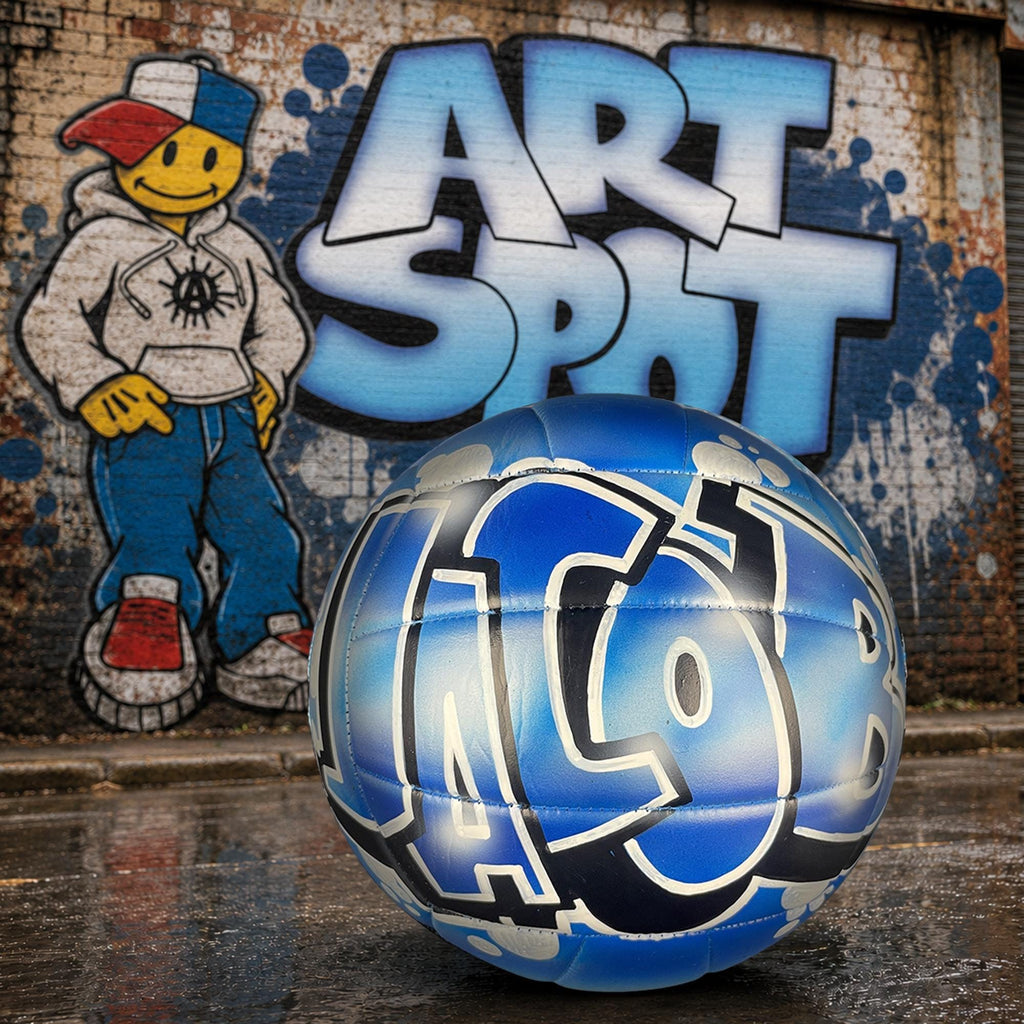 a blue and white custom volleyball personalized with graffiti on it, placed in front of a graffiti-covered wall with the word "ART SPOT" written on it.