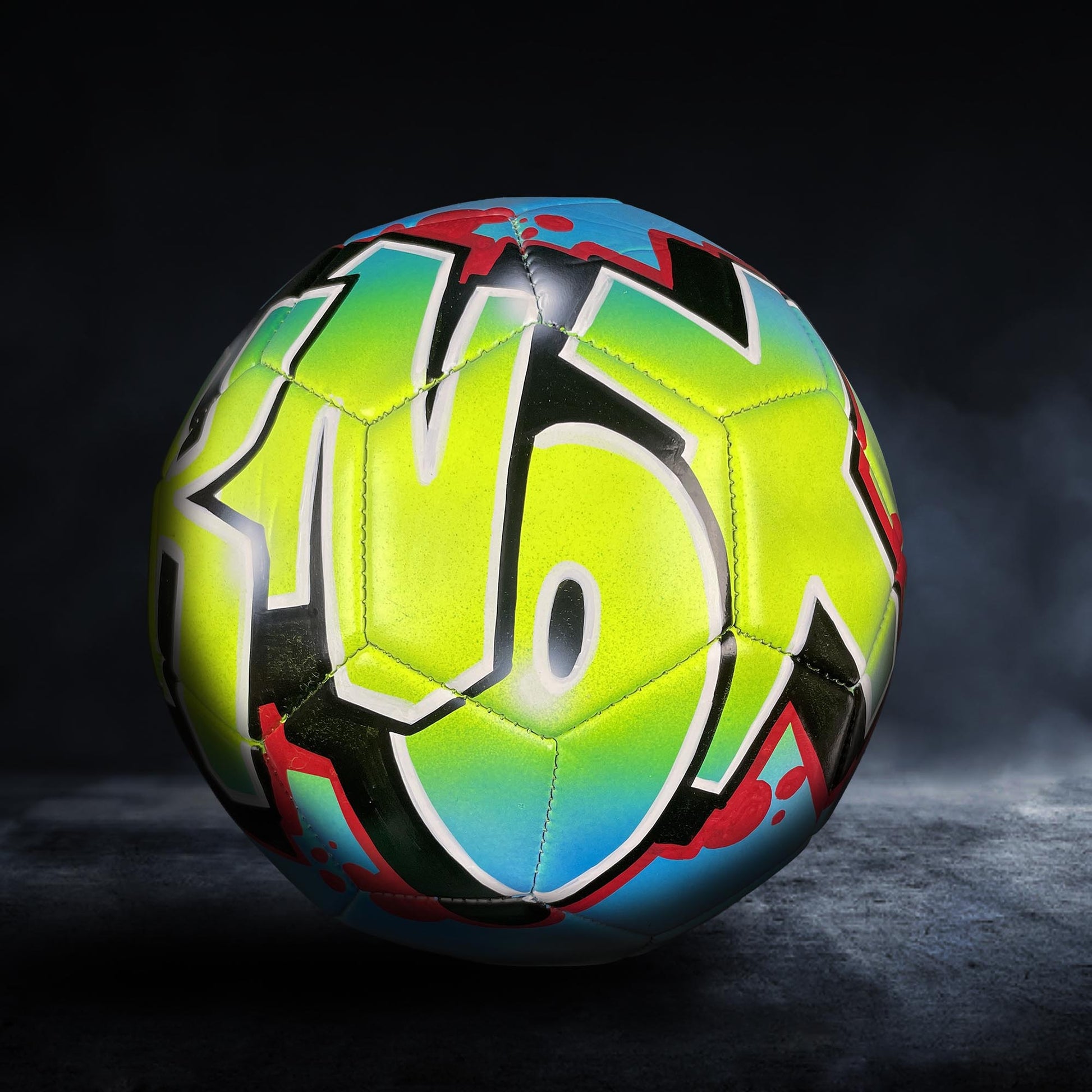 A colorful soccer ball with graffiti-style lettering on it, set against a dark background.