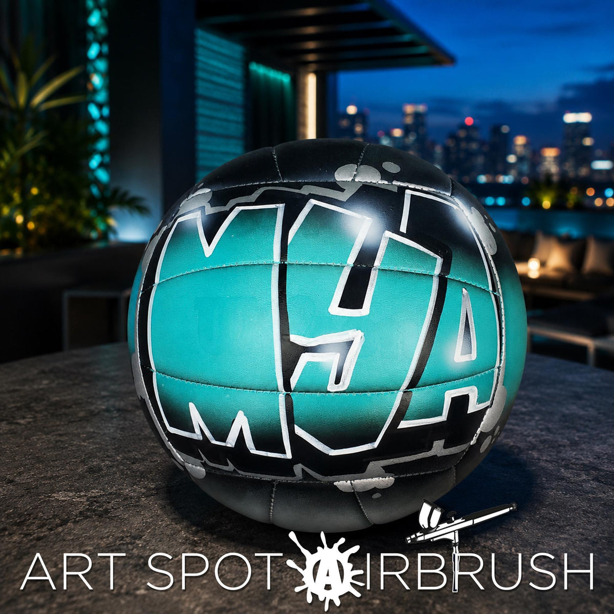 A neon-colored neon green and black personalized custom volleyball with the text "MYA" painted on it, placed on a table with a city skyline visible in the background.