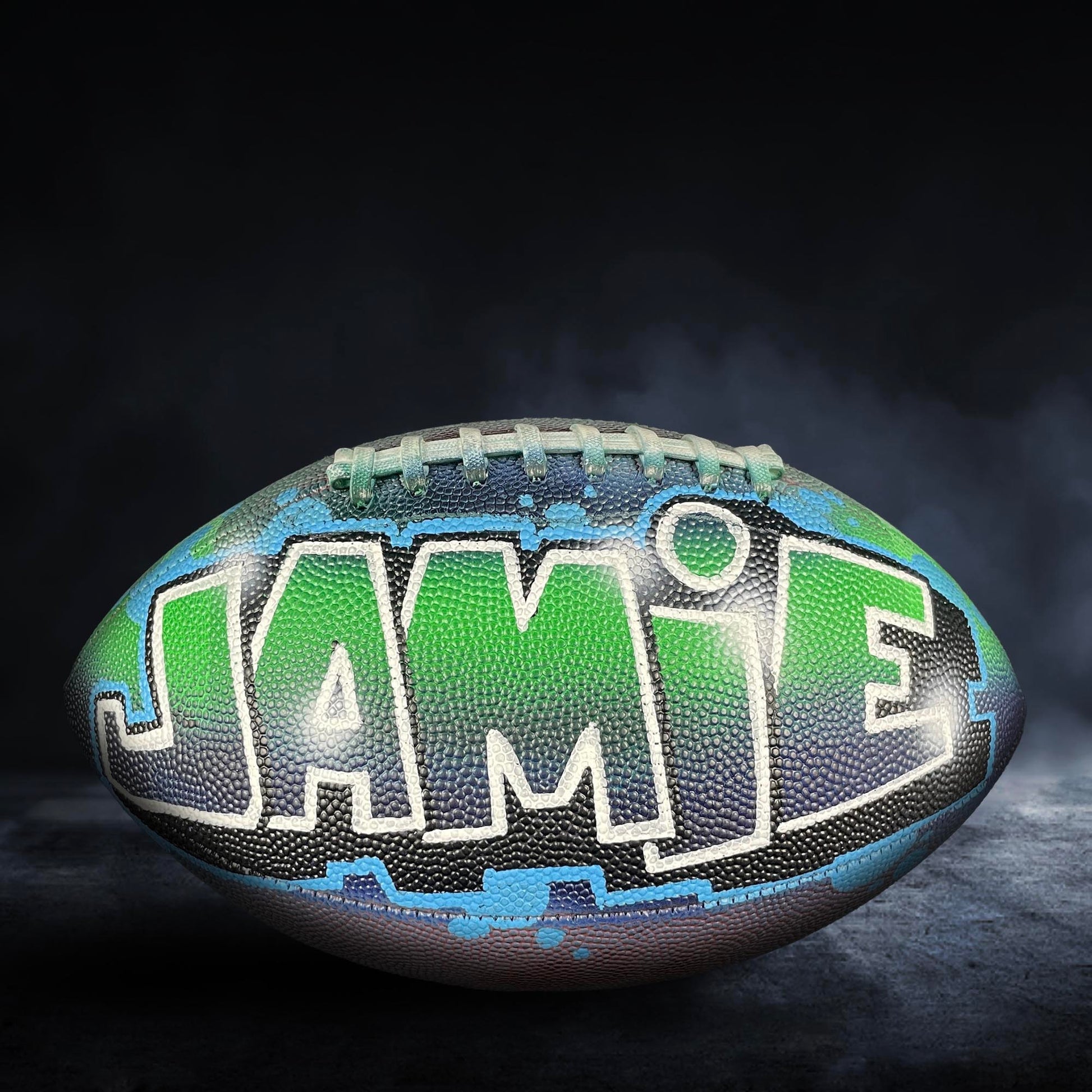 A personalized football with the name "JAMIE" painted on it.