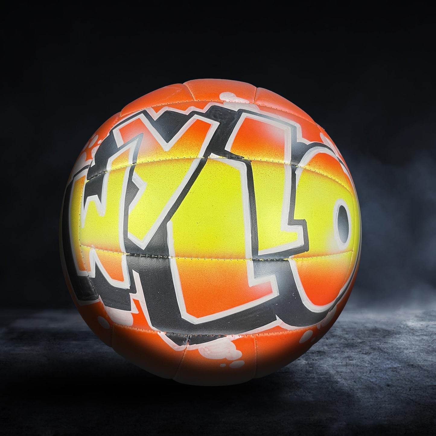 A colorful sports ball with graffiti-style text on it, set against a dark background.