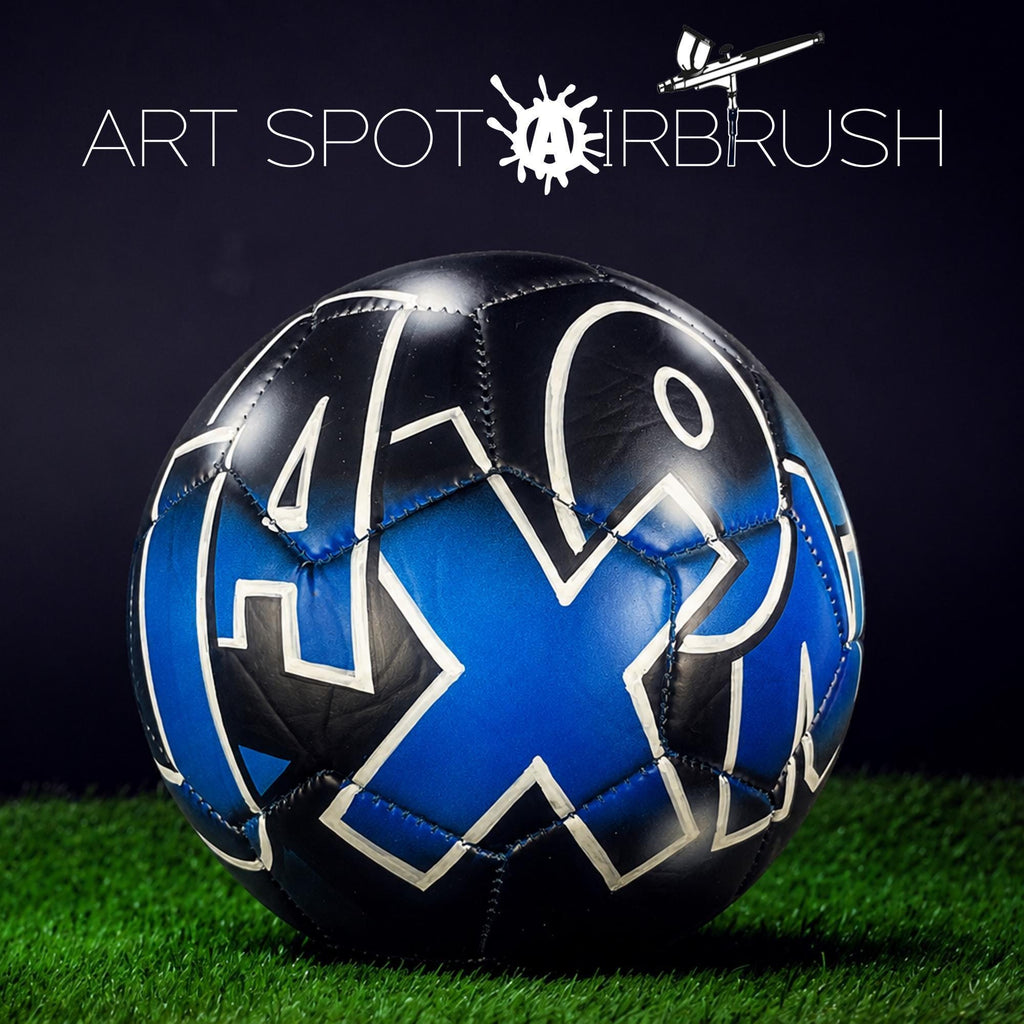 a soccer ball with a blue and black design on it, placed on a grassy surface.