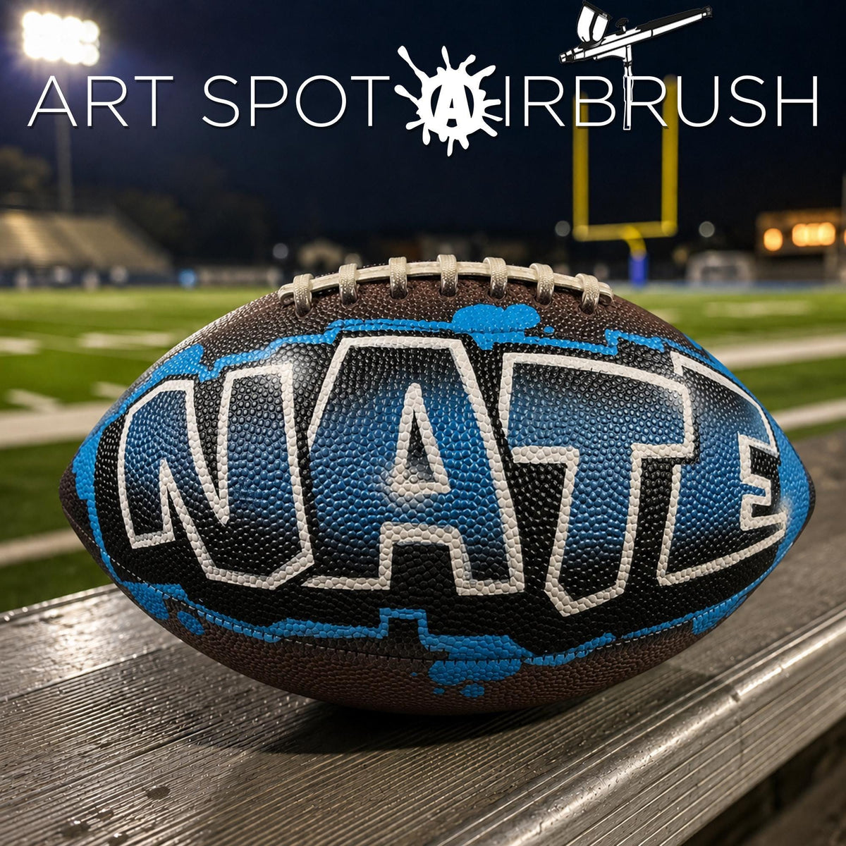 A custom football personalized with the word "NATE" painted on it, sitting on a wooden surface.