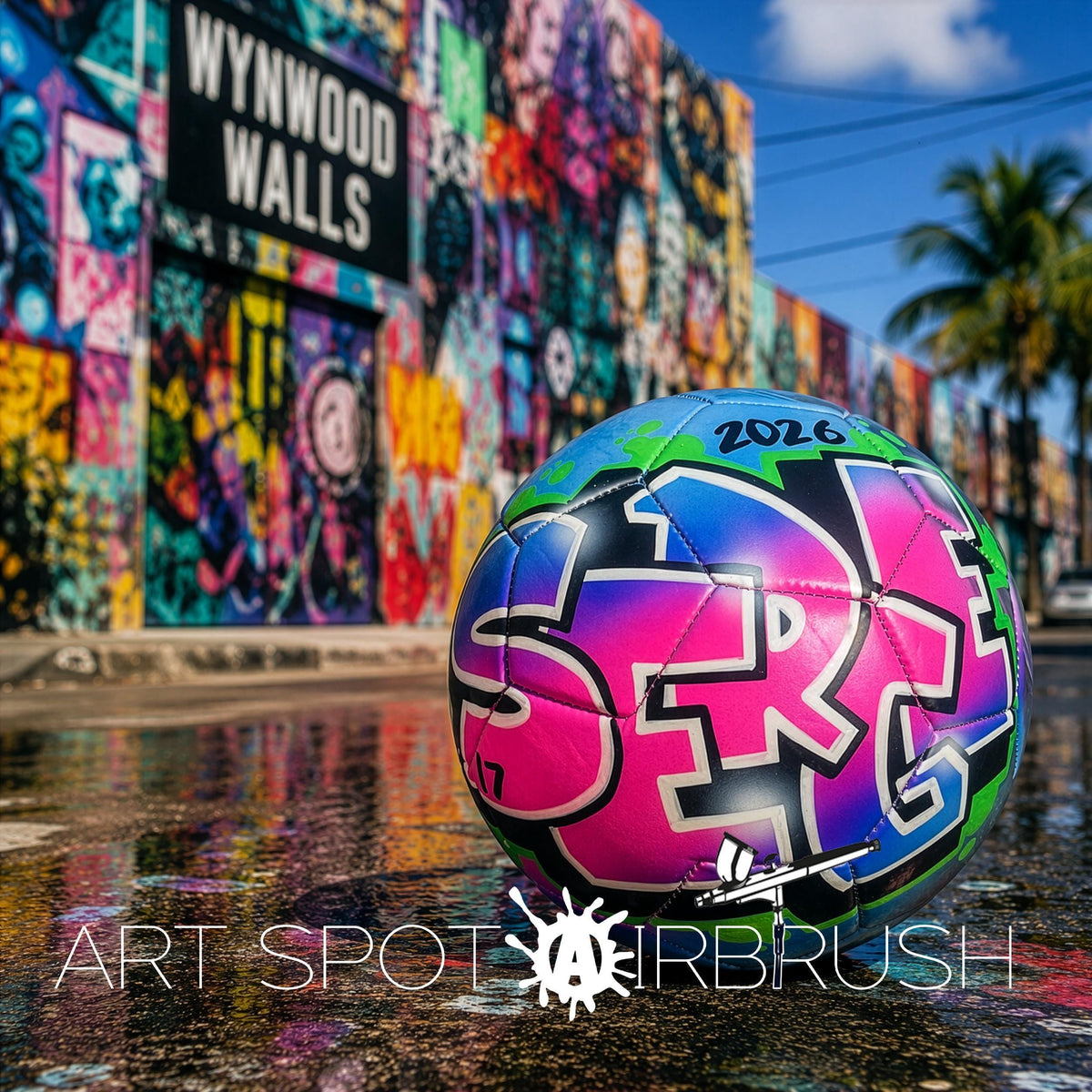 A colorful graffiti-covered wall in Wynwood Walls, with a soccer ball featuring the year "2026" on it, resting on a wet surface.