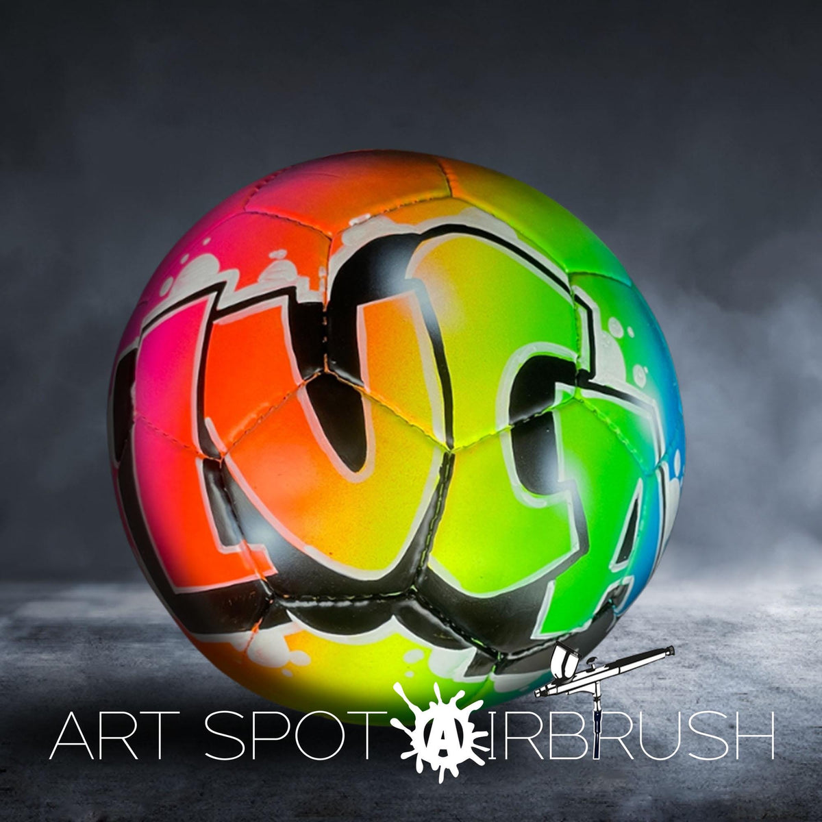 A colorful soccer ball with graffiti-style lettering on it, placed on a dark surface.