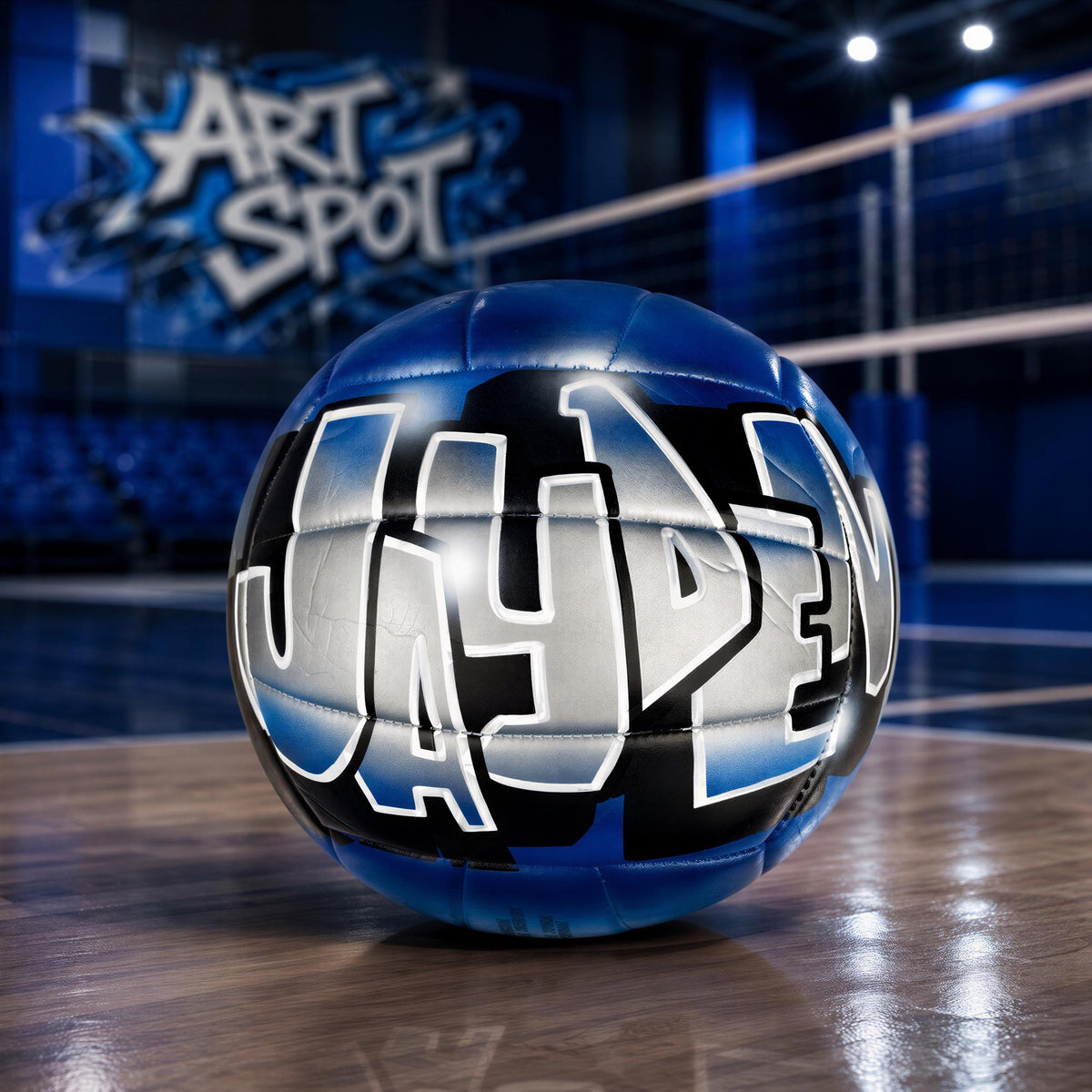 A blue and black volleyball with the word "JAYDEN" painted on it, sitting on a wooden surface.