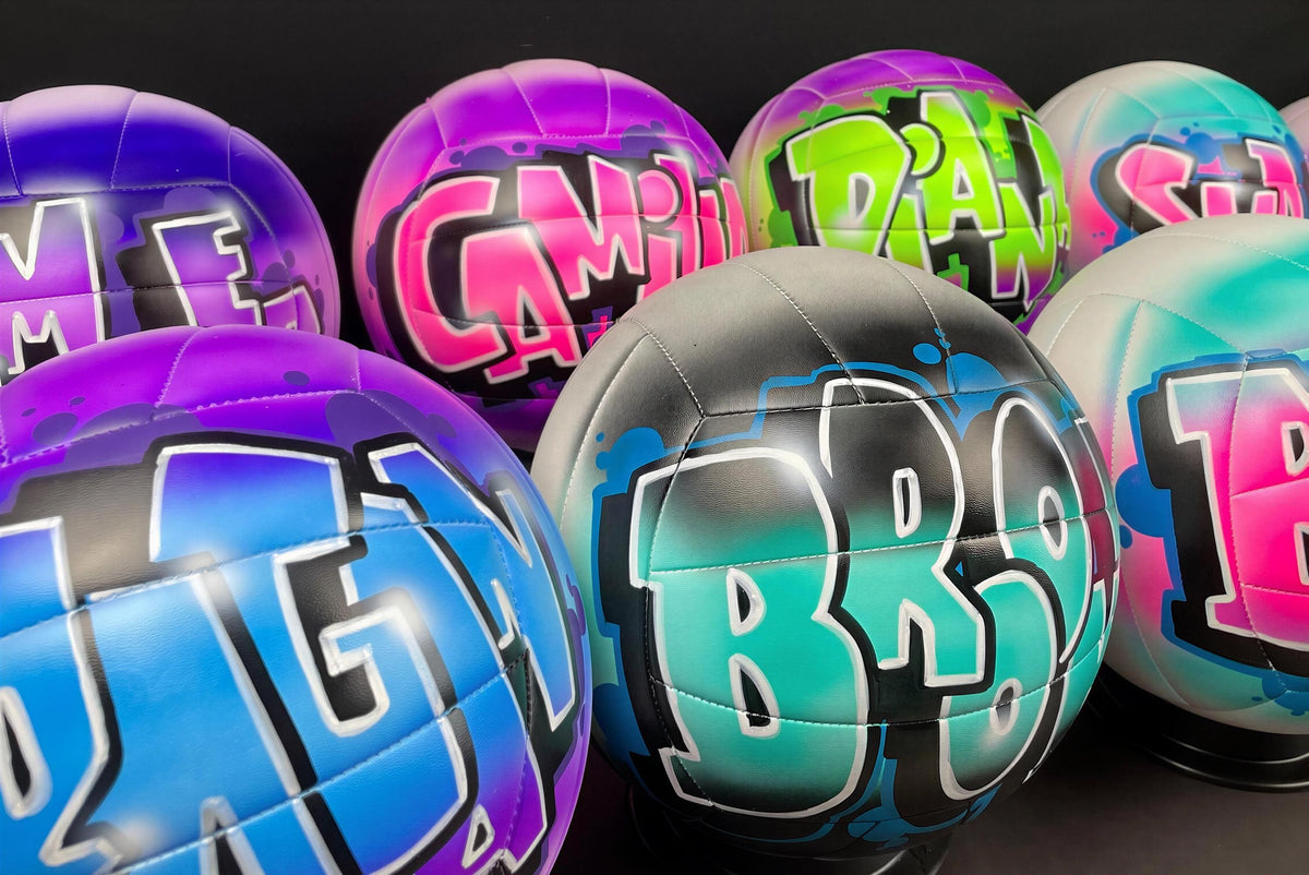 A collection of colorful, graffiti-style sports balls with various names and designs painted on them.