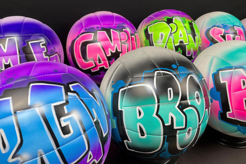 A collection of colorful, graffiti-style sports balls with various names and designs painted on them.