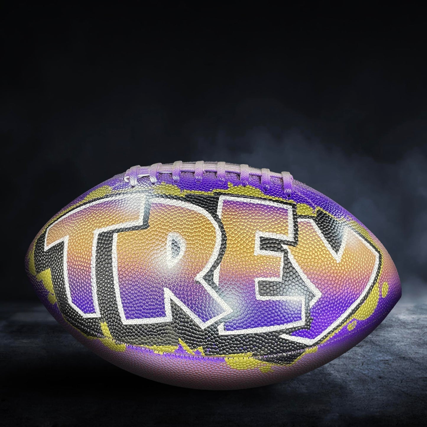 A personalized football with the name "TREY" painted on it.