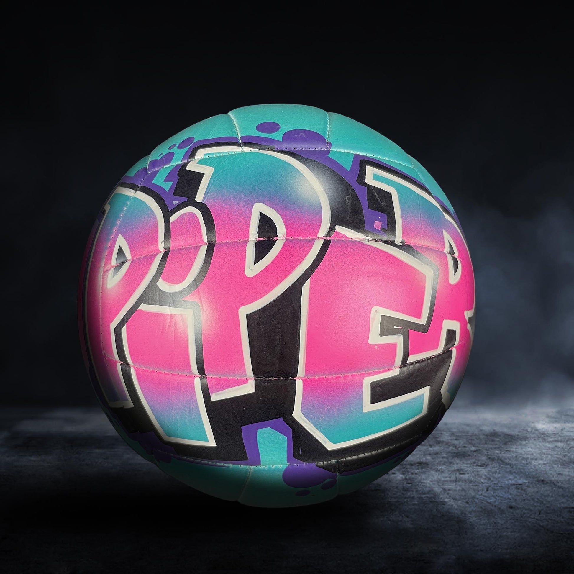 A colorful volleyball with the word "PEP" painted on it, set against a dark background.