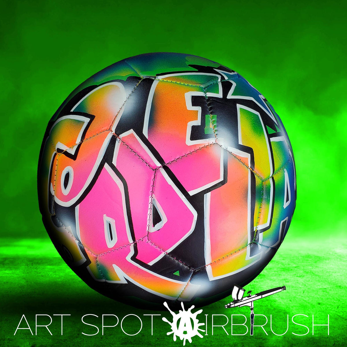 A colorful soccer ball with graffiti-style lettering on it, set against a green background.