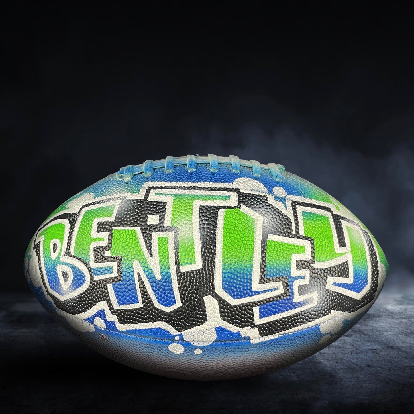 A football with the word "BENTLEY" painted on it in graffiti-style lettering.