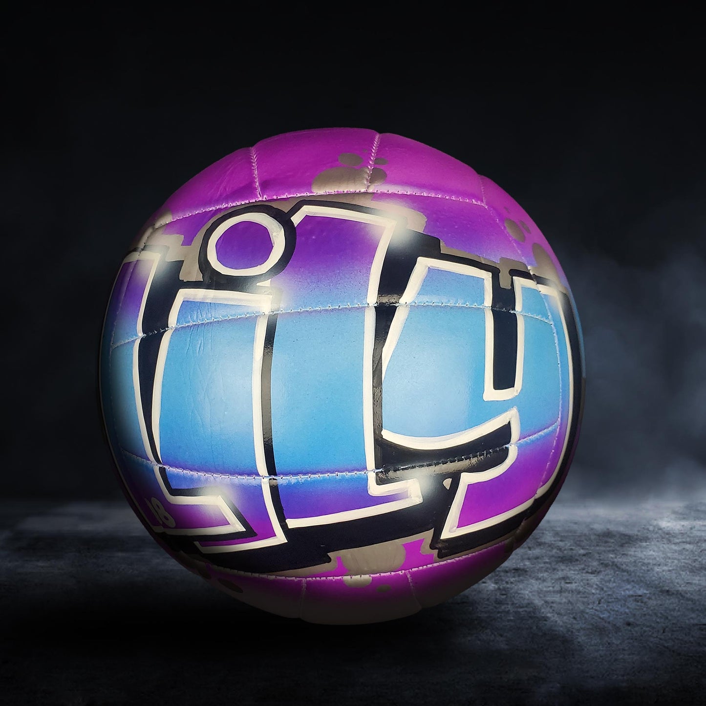 A colorful, graffiti-style volleyball with the word "LOUIS" painted on it, set against a dark background.