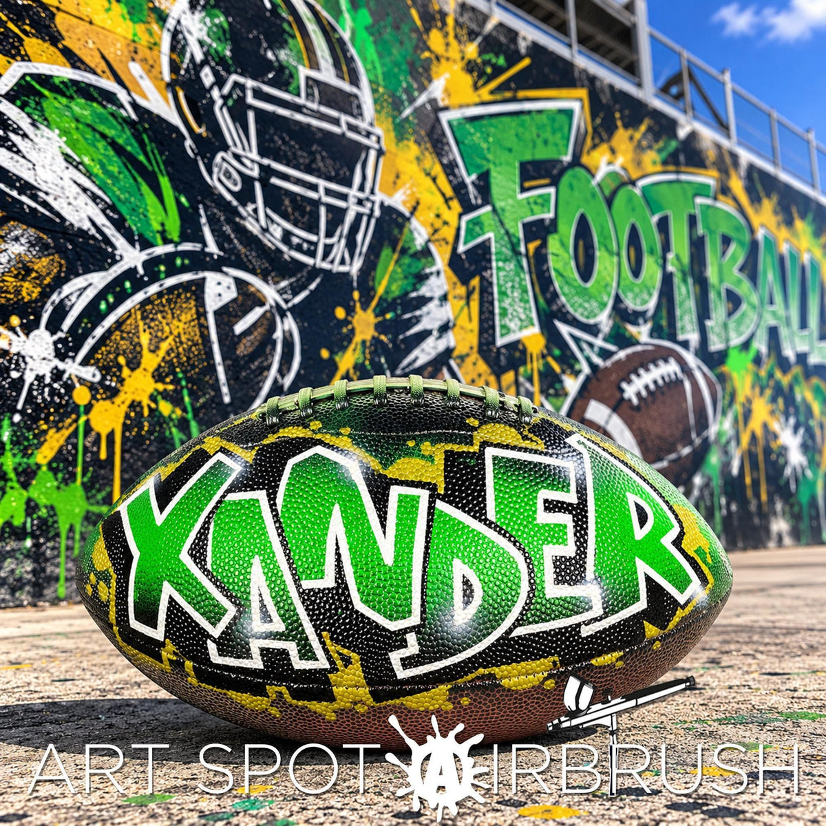 A personalized custom football with the name "xander" painted on it, along with a graffiti-style wall in the background.
