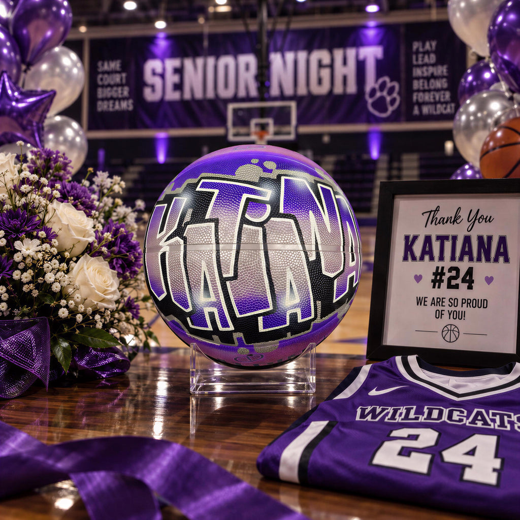 a basketball with the name "Katiana" painted on it, surrounded by purple and white decorations, including balloons and flowers. There is also a framed sign that says "Thank You Katiana #24 We are so proud of you!"