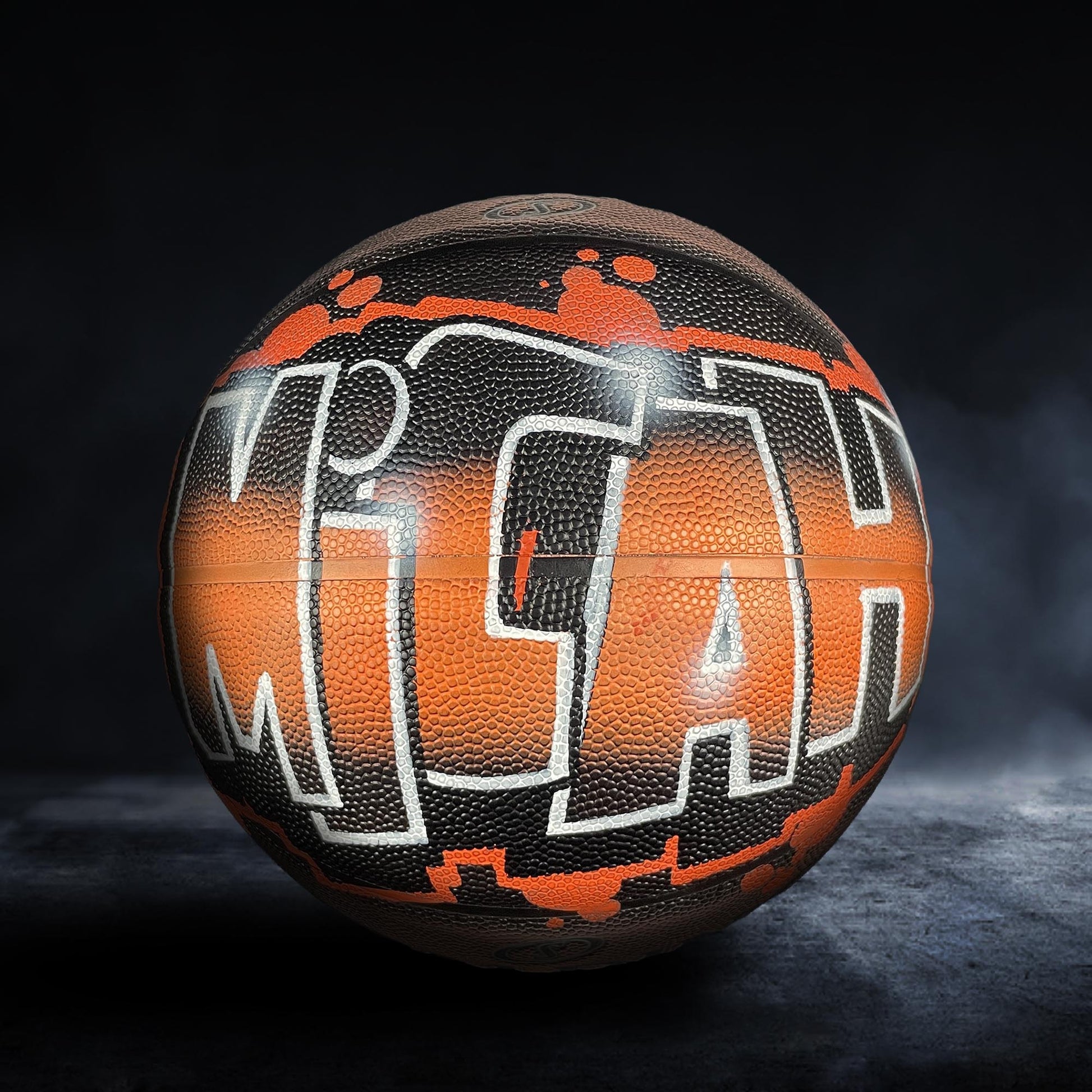 A basketball with the word "MICHIGAN" painted on it in a stylized, graffiti-like design.