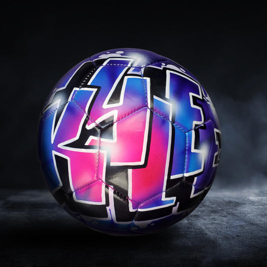 A colorful soccer ball with graffiti-style lettering on it, set against a dark background.