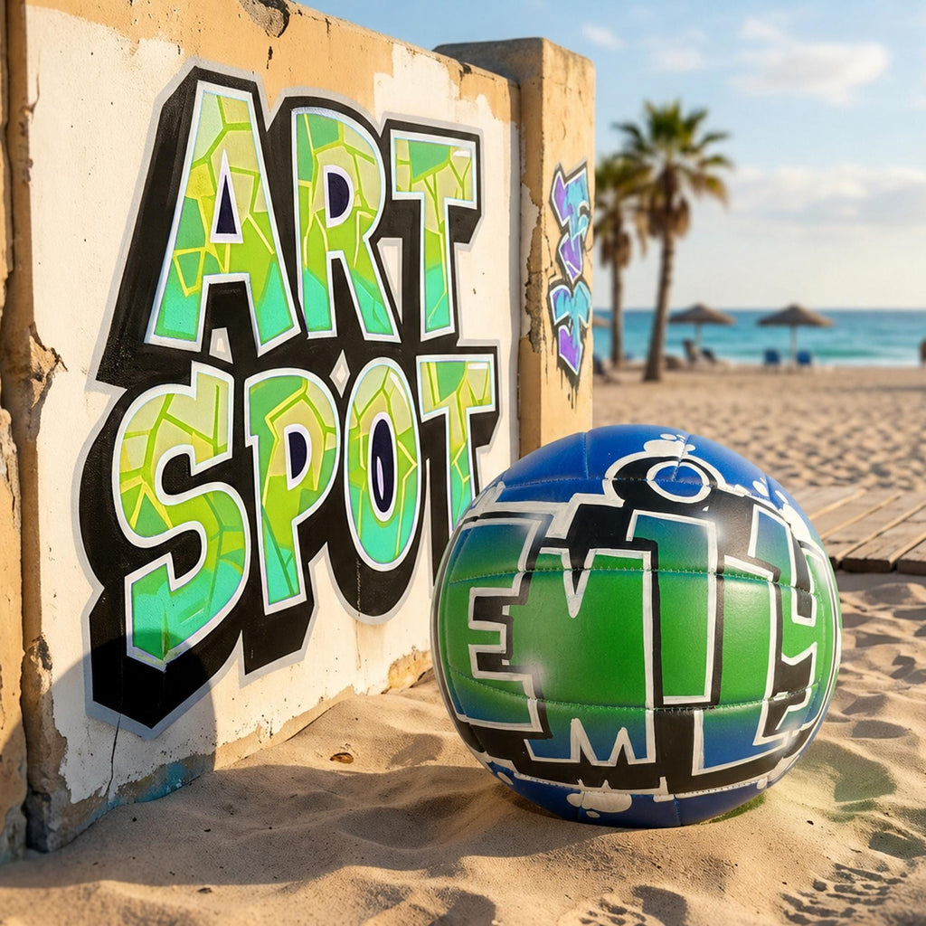 a beach scene with a large graffiti-style sign that says "ART SPOT" in bold, colorful letters, and a custom volleyball personalized with the name "EMILY" painted on it, sitting on the sand.