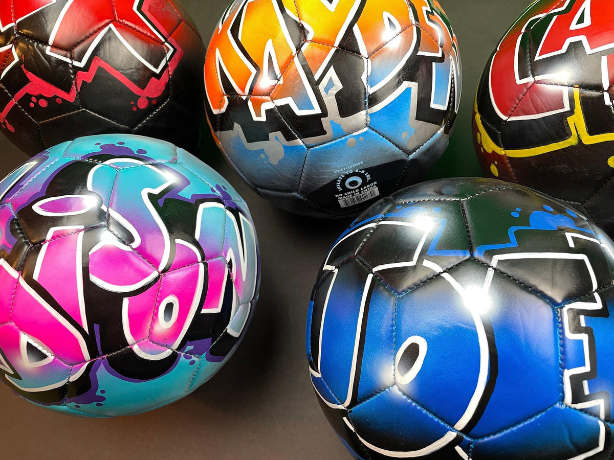 A group of colorful soccer balls with graffiti designs on them.