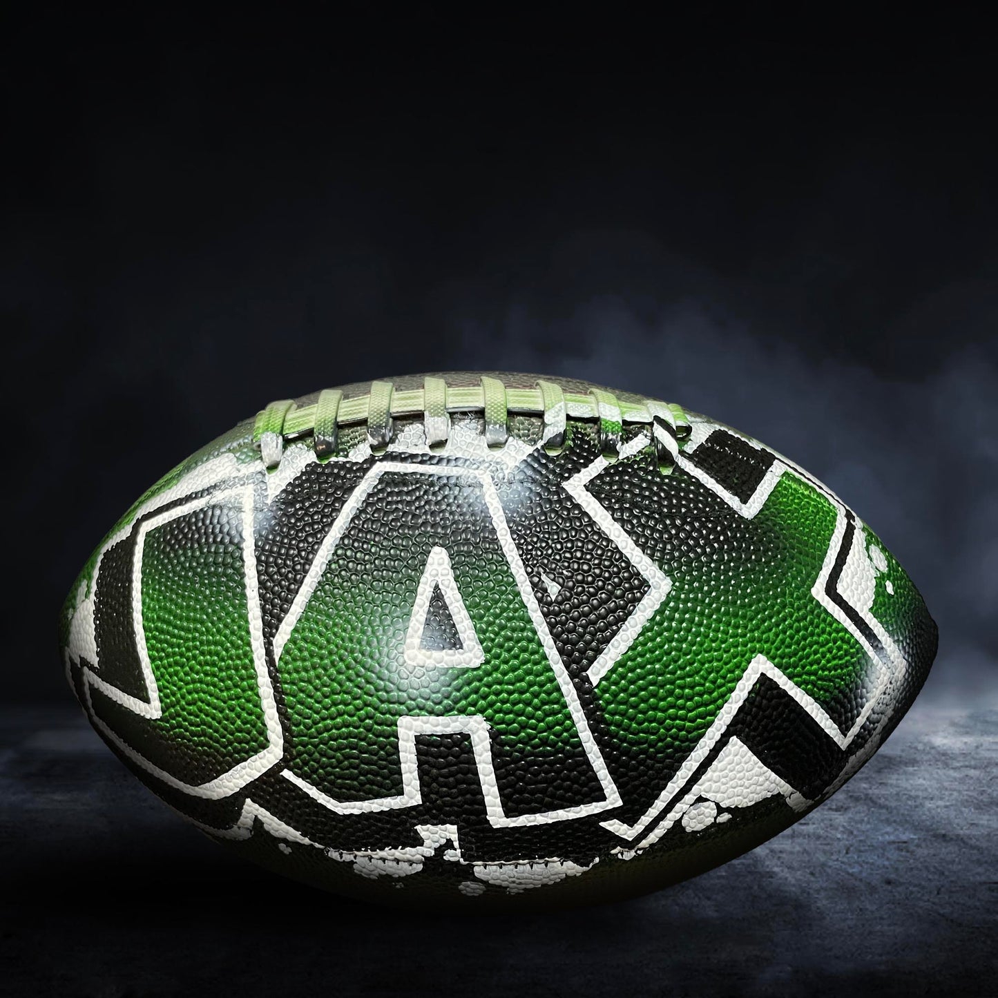 A football with the word "JAX" written on it, sitting on a dark surface with a misty background.