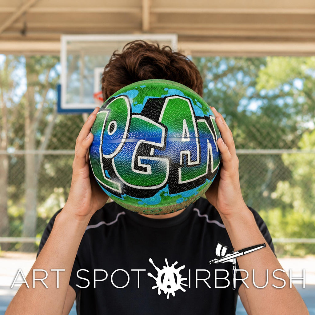 A person holding a basketball with the word "EAGAN" painted on it, partially covering their face.