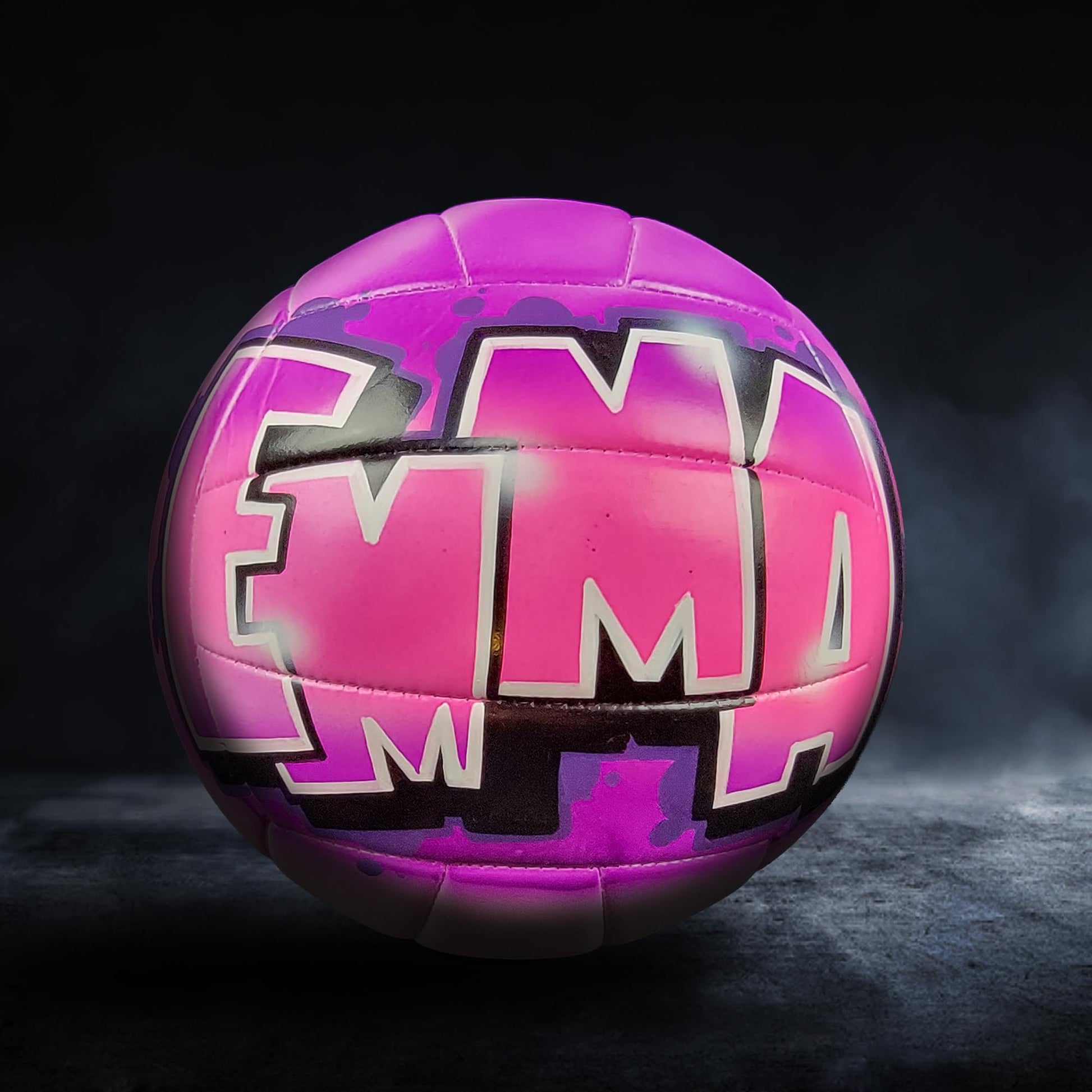 A purple volleyball with the word "Emma" painted on it, standing on a dark surface.